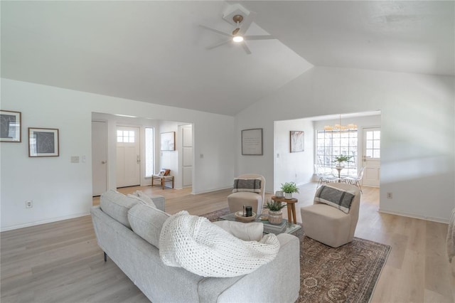 living room with lofted ceiling, ceiling fan with notable chandelier, light wood-type flooring, and baseboards