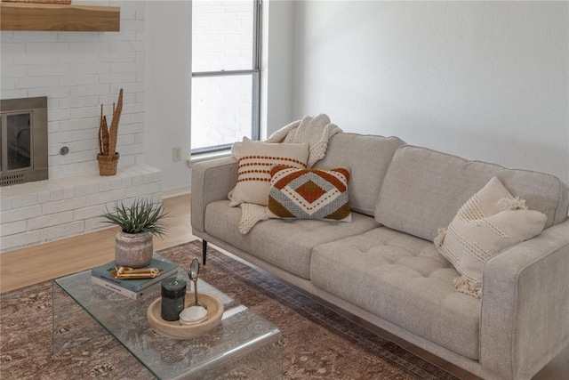 living area with a brick fireplace and wood finished floors