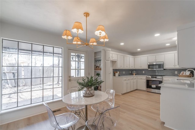 dining room with recessed lighting, light wood-type flooring, and a chandelier