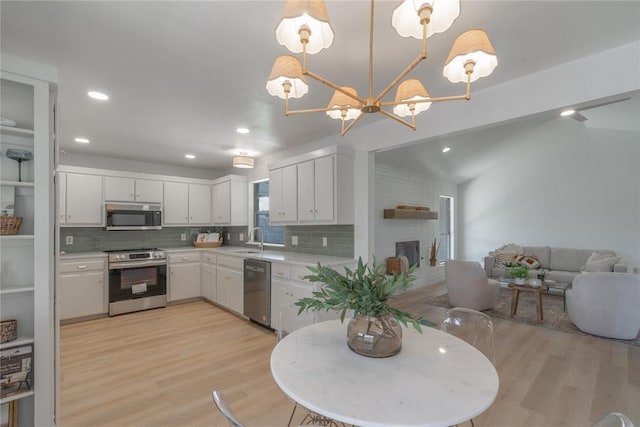 kitchen with an inviting chandelier, light countertops, light wood-type flooring, and stainless steel appliances