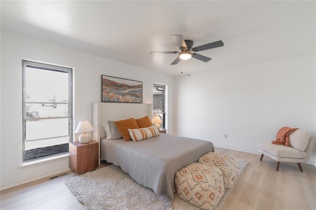 bedroom with visible vents, baseboards, a ceiling fan, and light wood finished floors