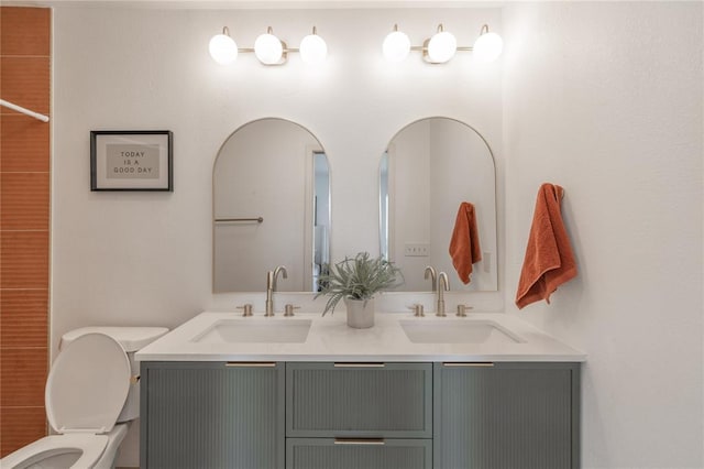 bathroom with double vanity, toilet, and a sink