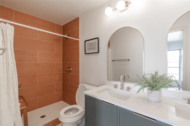 full bath featuring a sink, tiled shower, toilet, and double vanity