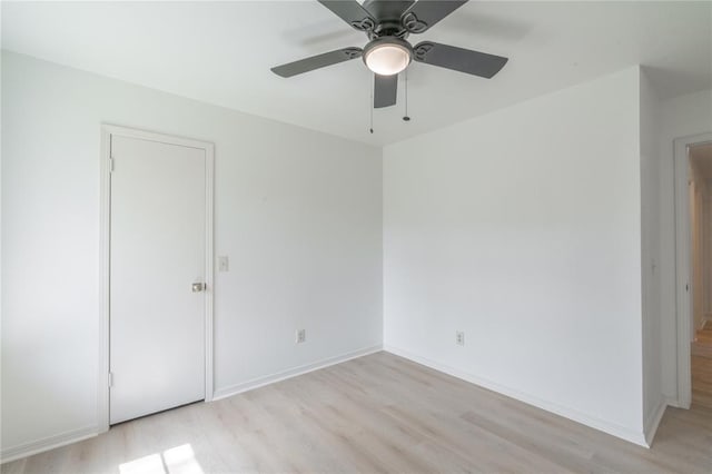 spare room featuring light wood-style flooring, baseboards, and ceiling fan