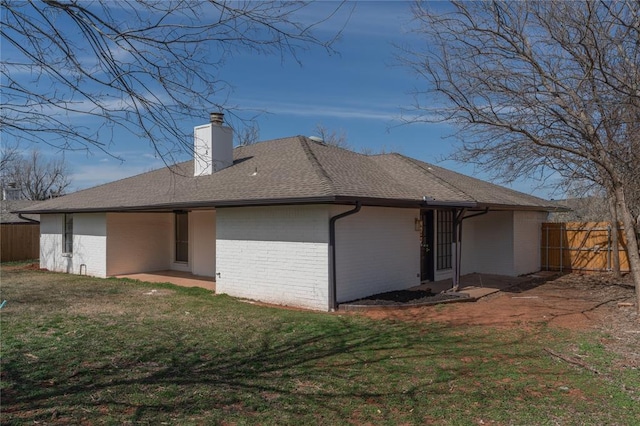 back of house with brick siding, a patio area, a lawn, and fence