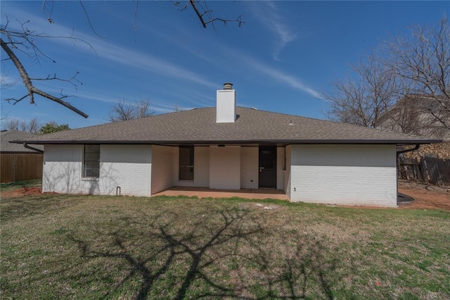 rear view of house featuring a patio, fence, a chimney, a lawn, and brick siding