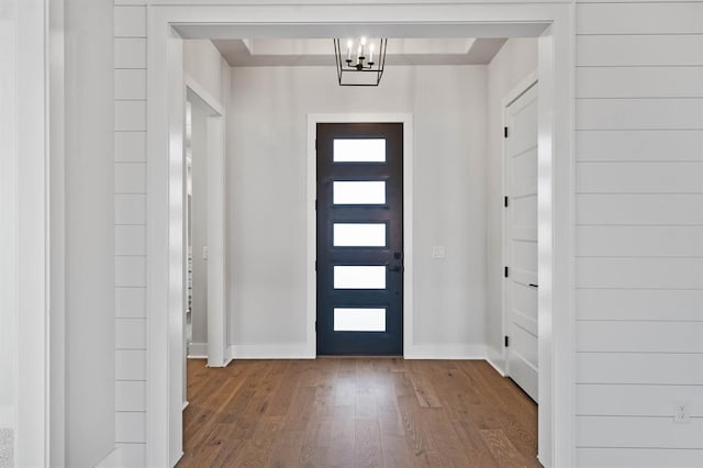 foyer entrance featuring baseboards, wood-type flooring, and a notable chandelier