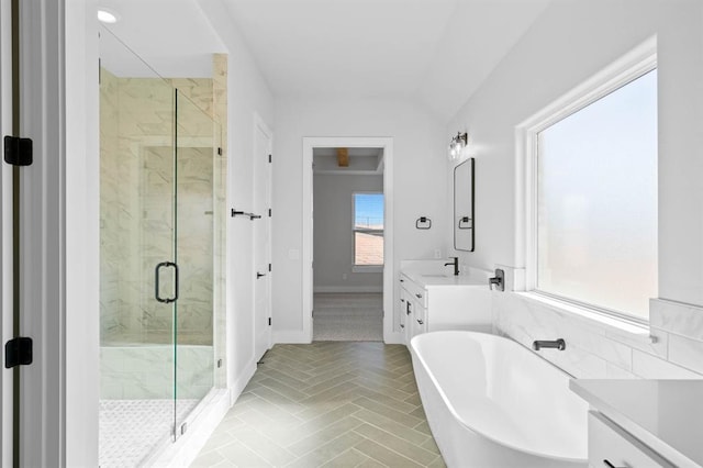 bathroom featuring a marble finish shower, vanity, baseboards, and a freestanding tub