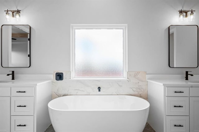 full bathroom with tile walls, two vanities, a wainscoted wall, and a freestanding bath