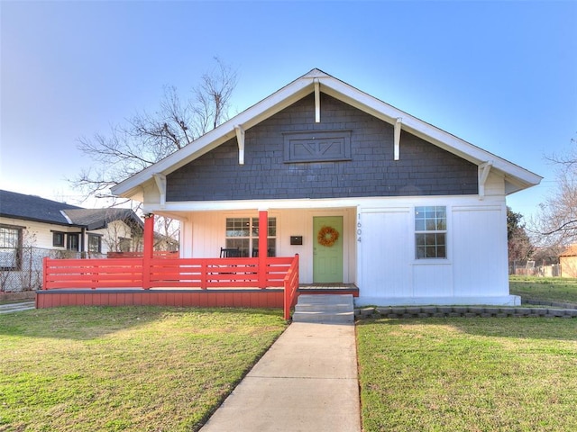 bungalow-style house with a porch, a front lawn, and fence