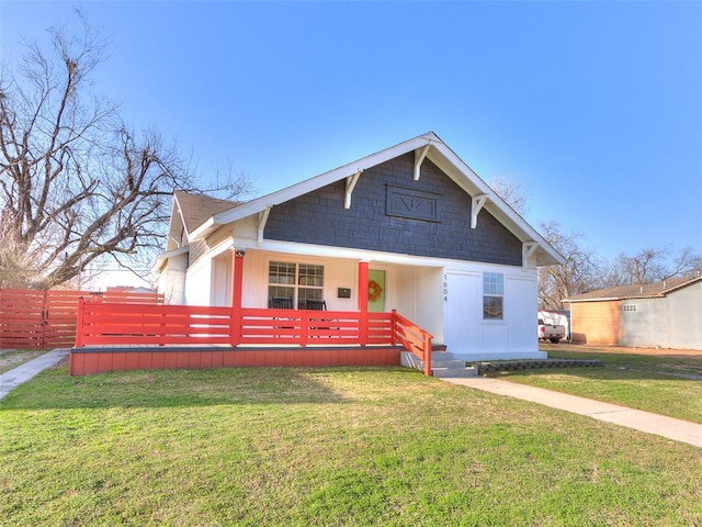 bungalow-style home with a porch, roof with shingles, a front yard, and fence