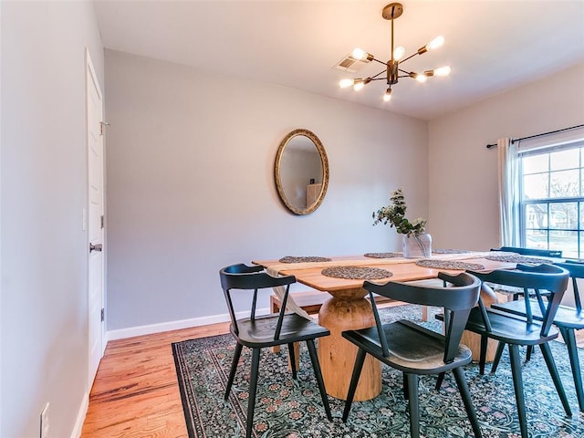 dining room with light wood-style flooring, a notable chandelier, visible vents, and baseboards