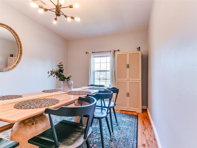 dining room featuring light wood-type flooring, baseboards, and a chandelier