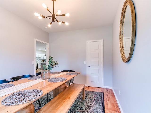 dining room with light wood-style flooring, baseboards, and a chandelier