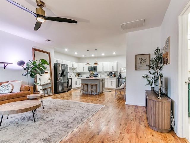 living area featuring recessed lighting, visible vents, light wood-style flooring, and ceiling fan