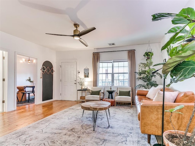 living room with ceiling fan, visible vents, and wood finished floors