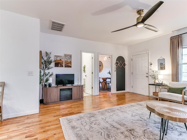 living area featuring visible vents, baseboards, light wood-style floors, and ceiling fan