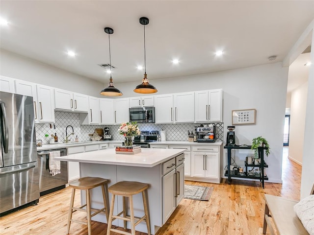 kitchen featuring a sink, stainless steel appliances, light wood finished floors, and light countertops