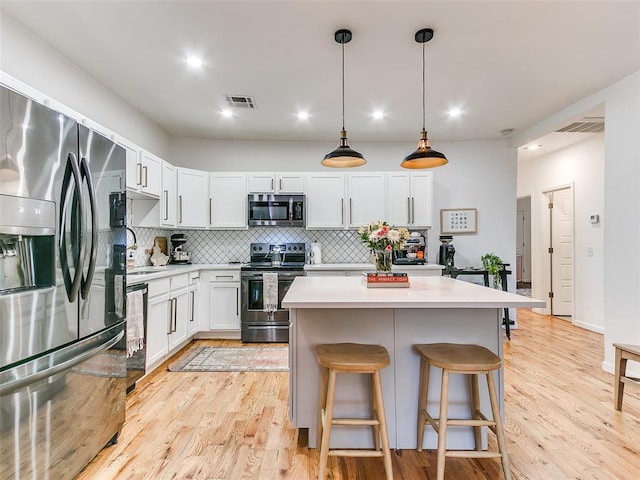 kitchen featuring light wood finished floors, a breakfast bar area, stainless steel appliances, and light countertops