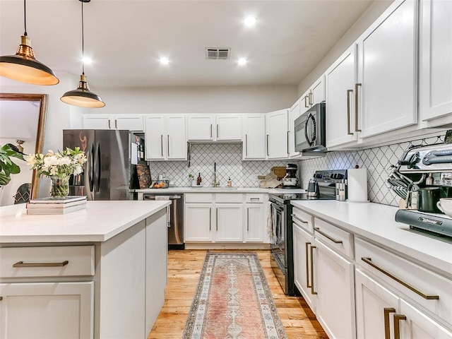 kitchen with a sink, visible vents, black appliances, and light countertops