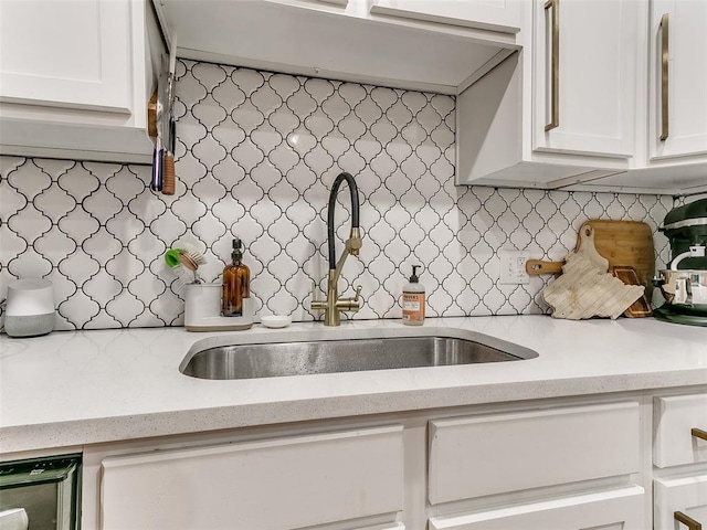 kitchen with white cabinetry, decorative backsplash, and a sink