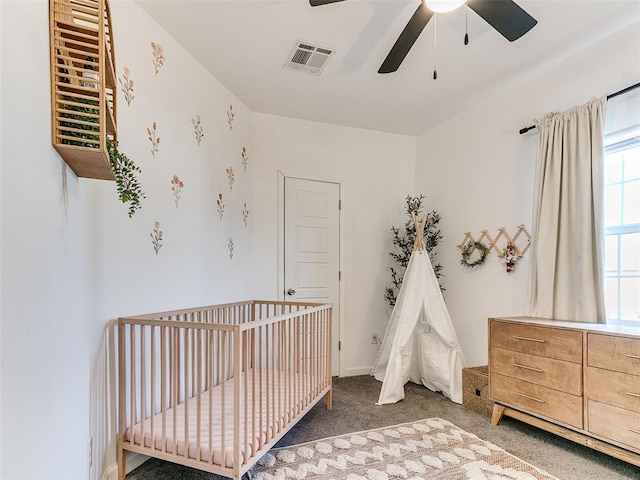 bedroom featuring a ceiling fan, a nursery area, carpet, and visible vents