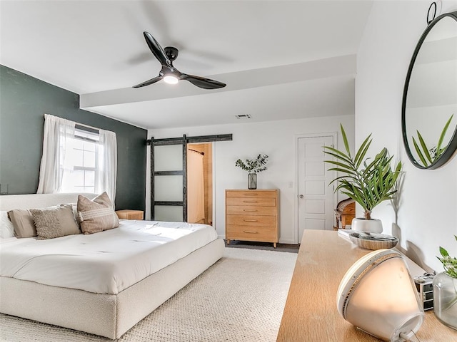 bedroom with visible vents, ceiling fan, and a barn door