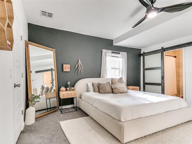 bedroom with visible vents, carpet flooring, a barn door, and ceiling fan