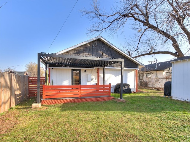 rear view of house featuring a wooden deck, a lawn, a fenced backyard, and a pergola