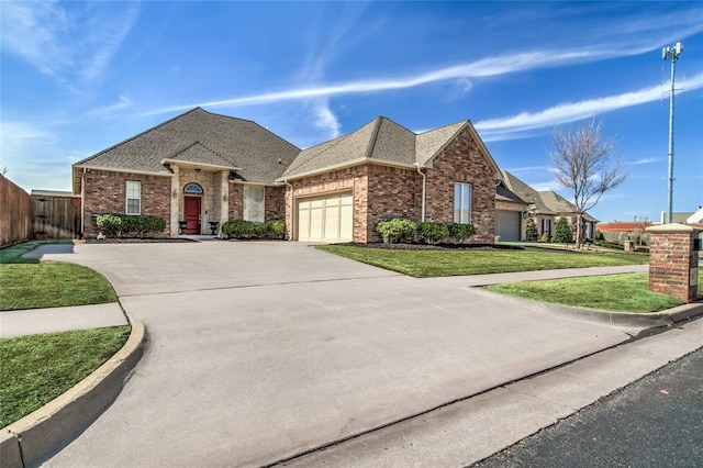 view of front of home with a front yard, fence, an attached garage, concrete driveway, and brick siding