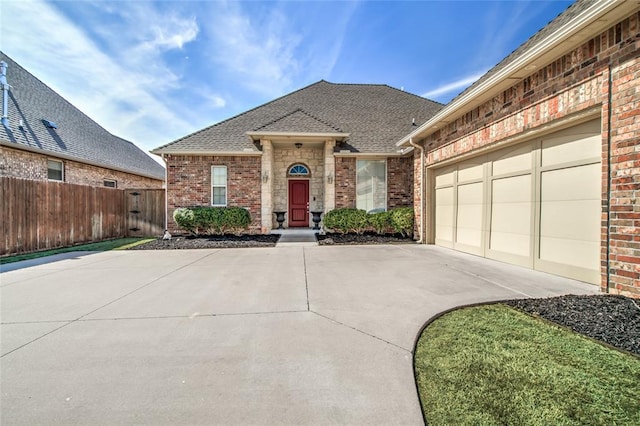 ranch-style house featuring brick siding, driveway, roof with shingles, and fence