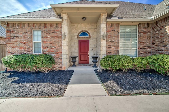 doorway to property featuring brick siding and a shingled roof