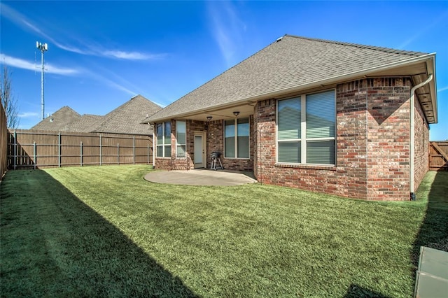 back of property featuring a patio, a fenced backyard, a shingled roof, a lawn, and brick siding