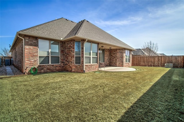 back of property with a patio area, brick siding, a lawn, and fence