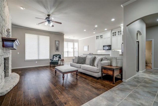 living room with wood finished floors, baseboards, a ceiling fan, arched walkways, and ornamental molding