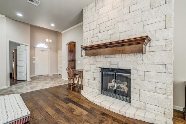 unfurnished living room featuring visible vents, baseboards, wood finished floors, and ornamental molding