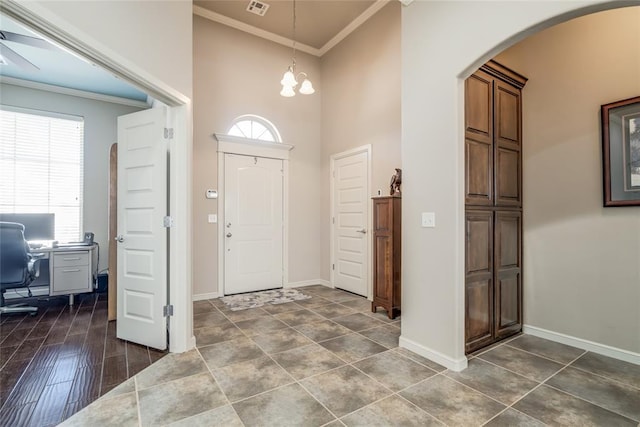 foyer with arched walkways, visible vents, crown molding, and baseboards