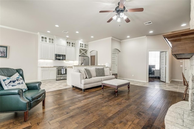 living area featuring baseboards, crown molding, a ceiling fan, and wood finished floors