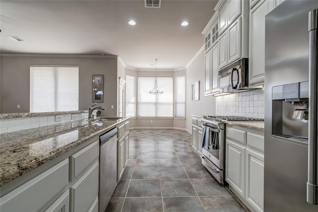 kitchen with a notable chandelier, a sink, backsplash, appliances with stainless steel finishes, and crown molding