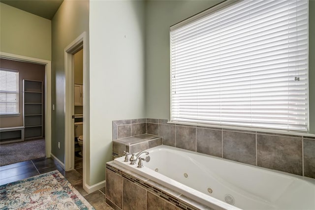 bathroom with tile patterned floors, toilet, and a whirlpool tub