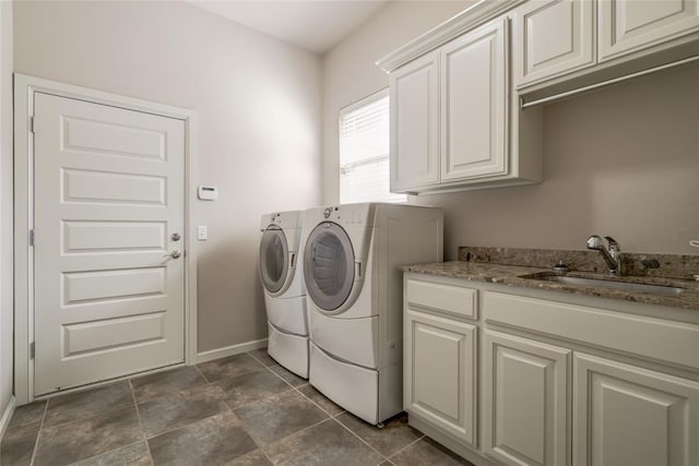 washroom featuring cabinet space, independent washer and dryer, baseboards, and a sink