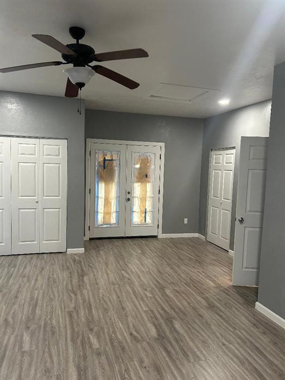 unfurnished living room with baseboards, a ceiling fan, attic access, wood finished floors, and french doors