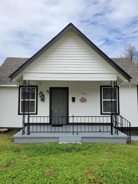view of front of house featuring a porch, roof with shingles, and a front lawn