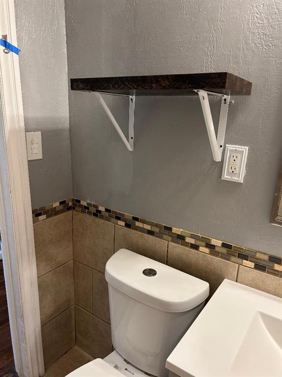bathroom featuring tile walls and toilet