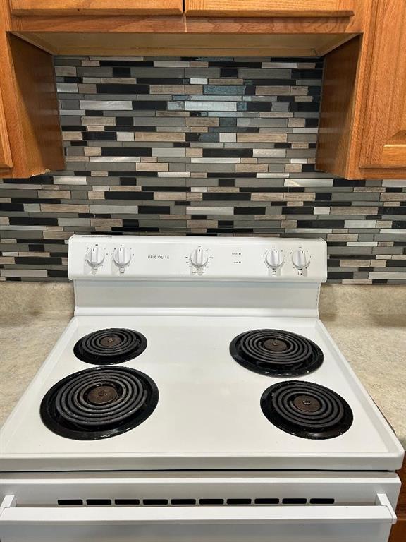 details with tasteful backsplash, light countertops, brown cabinetry, and electric stove