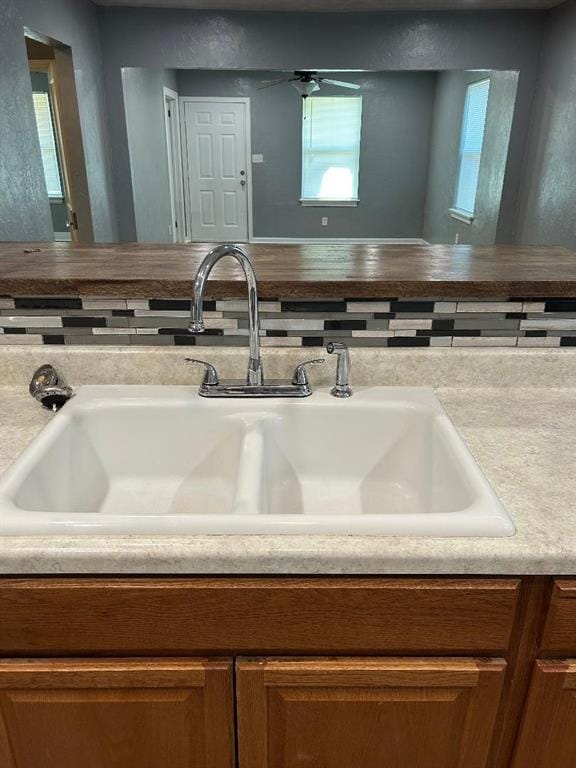 room details featuring brown cabinetry, a sink, and light countertops