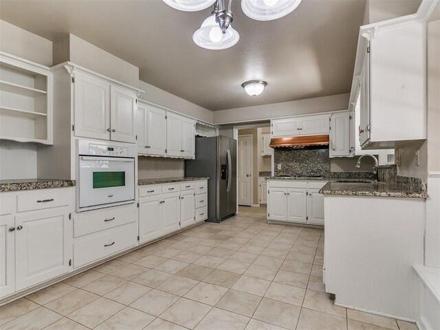 5700 N Billen Ave, Oklahoma City, OK 73112 - kitchen featuring oven, stainless steel refrigerator with ice dispenser, under cabinet range hood, a sink, and white cabinets