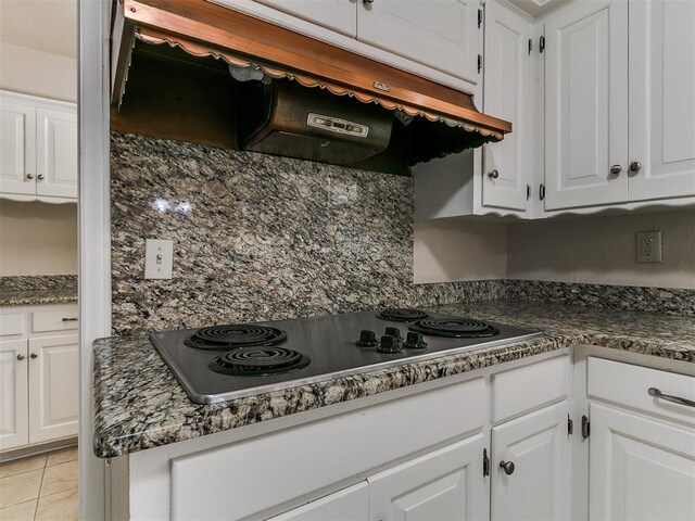 5700 N Billen Ave, Oklahoma City, OK 73112 - kitchen featuring dark countertops, under cabinet range hood, light tile patterned floors, stainless steel electric cooktop, and white cabinets