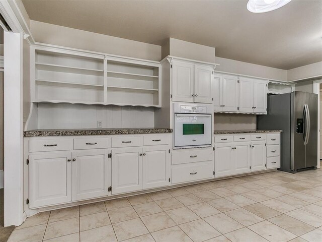 5700 N Billen Ave, Oklahoma City, OK 73112 - kitchen with oven, open shelves, white cabinetry, dark stone counters, and stainless steel fridge