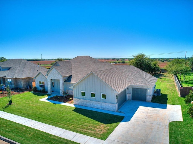 view of front facade featuring a front yard, driveway, stone siding, a garage, and board and batten siding